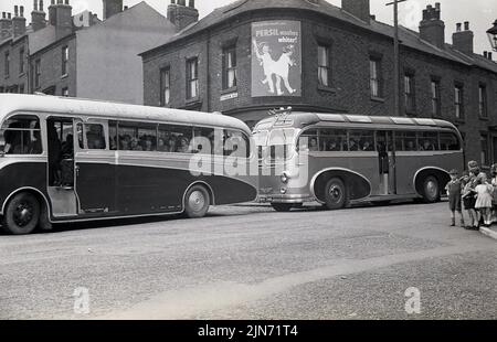 1950s, historisch, Busfahrt, Sheffield-Torquay Express. Passagiere, die in zwei Littlewood Bros-Bussen sitzen, die auf der Grimesthorpe Road vor Lily Bells Geschäft an der Ecke, Sheffield, South Yorkshire, England, Großbritannien, warten. Stockfoto
