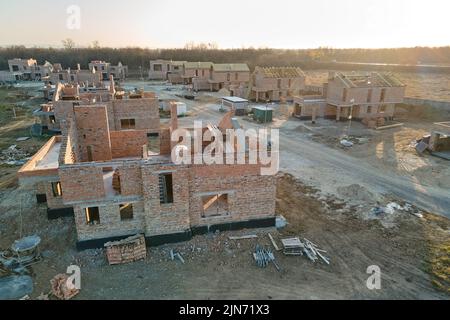 Luftaufnahme von neuen Häusern mit Backstein-Rahmenmauern im Bau in ländlichen Vorstadtbereich. Entwicklung von Immobilien in modernen Stadtvororten Stockfoto