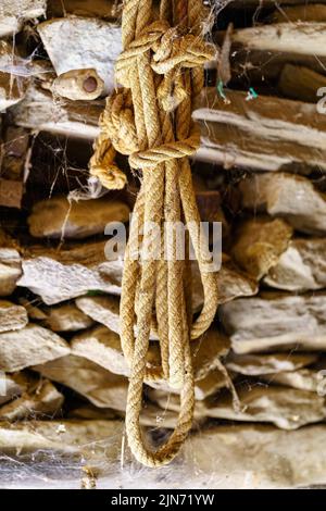 Seilseil für Feldarbeiten an einer Steinwand im Laufe der Jahre in einem Zustand der Verlassenheit verwendet. Stockfoto