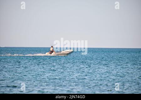 Meereslandschaft mit Wellenoberfläche aus blauem Meerwasser mit weißem Schnellboot, das schnell auf ruhigen Wellen schwimmt Stockfoto