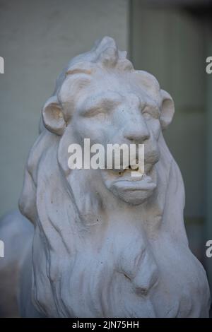 Steinlöwenskulptur am Eingang zu einem großen Haus, Steinskulptur eines Löwen, der den Eingang zu einem großen Haus bewacht, Gartenstatuar, Gartenornament Stockfoto