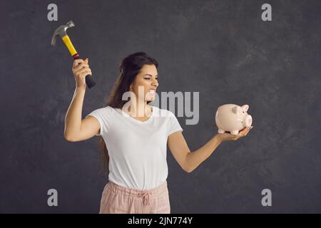 Wütend Frau brechen Sparschwein für Geld sparen Stockfoto