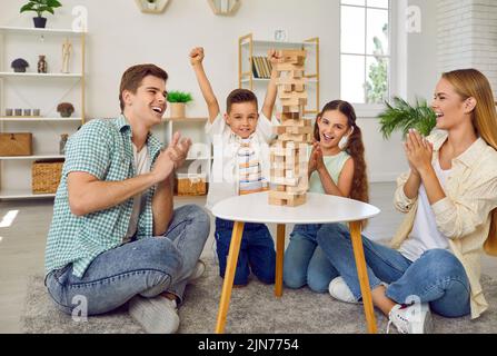 Fröhliche und freundliche junge Familie mit zwei Kindern hat Spaß, Jenga zusammen zu spielen. Stockfoto