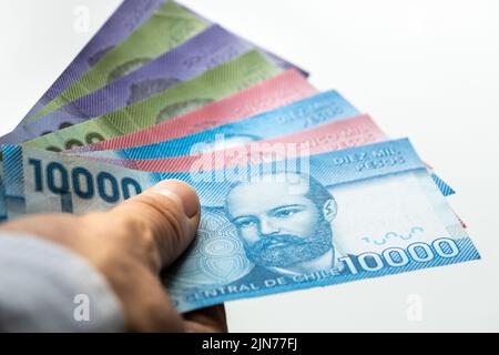 Chiles Geld, Papierpesos, auf weißem Hintergrund in der Hand gehalten, Nahaufnahme Stockfoto