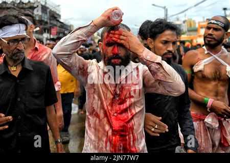 Kalkutta, Westbengalen, Indien. 9. August 2022. (HINWEIS DER REDAKTION: Das Bild enthält grafische Inhalte.) Ein schiitischer muslimischer Anhänger bedeckt sich mit Blut, nachdem er sich gefährlich mit Schwertern verletzte, während er während der Muharram-Prozession von Kalkutta seine Trauer zeigte. Muharram ist der erste Monat des islamischen Kalenders und Ashura ist der zehnte Tag des Monats Muharram, an dem die Erinnerung an das Martyrium von Imam Hussain, dem Enkel des Propheten Muhammad (PBUH), während der Schlacht von Karbala, erfolgt. Es ist Teil der Trauer um schiitische Muslime und ein Fastentag für sunnitische Muslime, der all o beobachtet wird Stockfoto