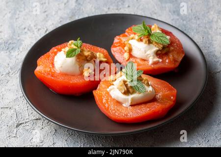 Traditionelles türkisches Quitten-Dessert. Die Quitte wird weich gekocht, darauf wird Sherbet gegossen und mit Rahm und Walnüssen serviert. Es ist einer der Th Stockfoto