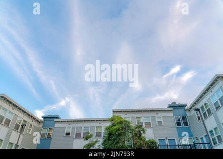 Apartmentkomplex mit U-förmiger Struktur am Himmel in San Francisco, CA. Es gibt Bäume an der Vorderseite des Wohngebäudes außen mit blu Stockfoto