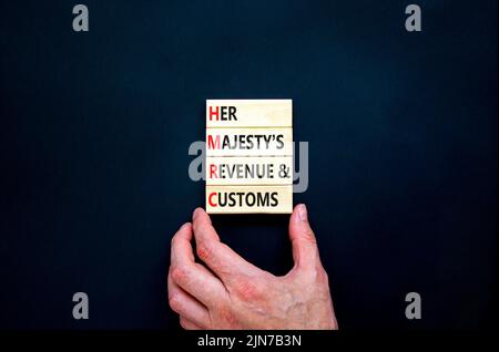 HMRC her majestys Einkommens- und Zollsymbol. Konzept Wörter HMRC her majestys Umsatz und Zoll auf Blöcken auf schönen schwarzen Hintergrund. Business-HM Stockfoto