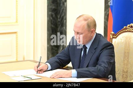 Moskau, Russland. 09. August 2022. Der russische Präsident Wladimir Putin notiert sich bei einem Telefonkonferenz-Treffen mit dem amtierenden Gouverneur der Kirower Region Alexander Sokolov vom Kreml am 9. August 2022 in Moskau, Russland. Quelle: Mikhail Klimentyev/Kremlin Pool/Alamy Live News Stockfoto