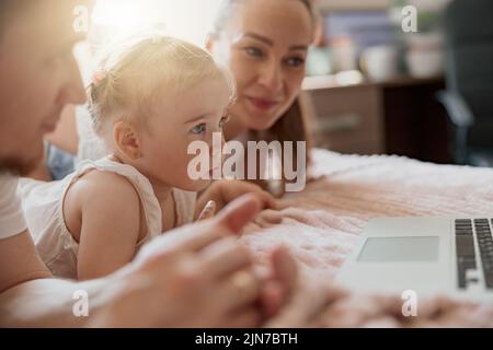 Nahaufnahme der glücklichen Familie, die Spaß miteinander haben, Cartoons online auf dem Laptop zu sehen, liegen auf dem Sofa zu Hause Stockfoto
