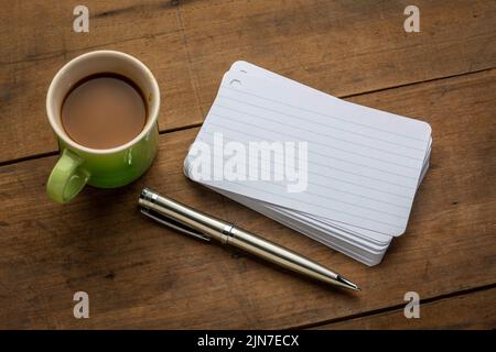 Ein Stapel leerer Karteikarten mit einer Tasse Kaffee und einem Stift gegen strukturierte Rinde Papier Stockfoto