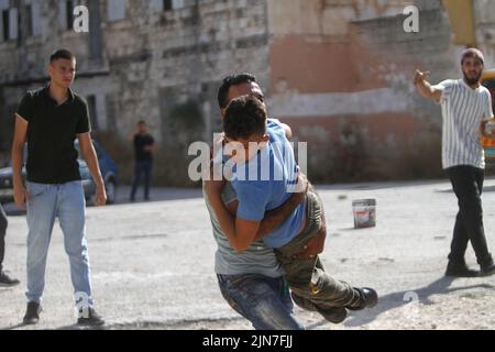 Nablus, Palästina. 02. August 2022. Ein Palästinenser, der während der Zusammenstöße mit israelischen Armeekräften einen verletzten Protestierenden nach einem Überfall in der Altstadt von Nablus im besetzten Westjordanland tragen sah, teilte das palästinensische Gesundheitsministerium mit, dass 3 Palästinenser während des Überfalls getötet wurden. (Foto von Nasser Ishtayeh/SOPA Images/Sipa USA) Quelle: SIPA USA/Alamy Live News Stockfoto