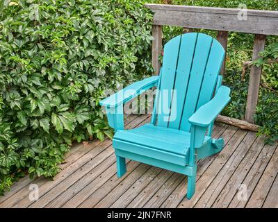 Leerer Adirondack-Stuhl auf einer hölzernen Hinterhofterrasse, Sommerlandschaft in Colorado Stockfoto