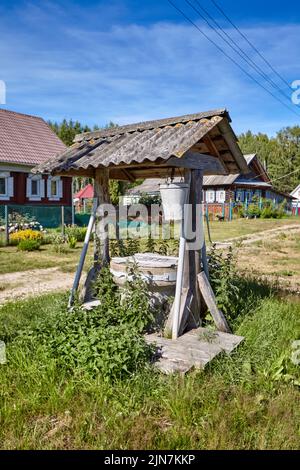 Traditioneller russischer alter Wasserbrunnen im Dorf. Ländliche Landschaft Stockfoto