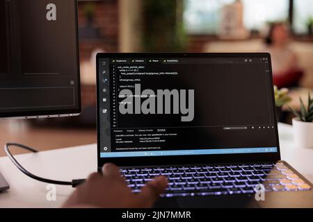 Männlicher Programmierer mit Coding Encryption Interface App auf Laptop-Bildschirm, arbeiten mit Binärcode und Cloud-Server. Programmiergerät, das eine Sicherheitsfirewall auf dem Terminalfenster programmiert. Nahaufnahme. Stockfoto