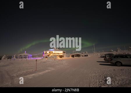Die Nordlichter über dem ländlichen Haus auf dem schneebedeckten Feld Stockfoto