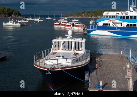 Ein großes Vergnügungsboot, das an einem Dock in der Frenchman Bay von Bar Harbor, Maine, USA, mit vielen Booten vor Anker gebunden ist. Stockfoto