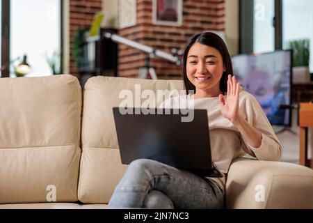 Lächelnd schöne authentische asiatische Frau auf Online-Internet-Web-Technologie Videoanruf Verzicht auf Kamera, zu Hause Freizeit Lifestyle digitale Web-Kommunikation Webcam Chat Freelacer zu Hause Stockfoto