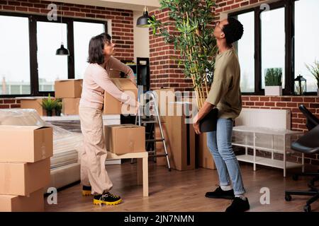 Diverse paar Kauf erste Heimat und Umzug zusammen, Auspacken Anlage und Möbel, um neuen Haushalt zu schmücken. Genießen Sie den Umzug von Immobilien mit Dekor, um neue Lebensstile zu beginnen. Stockfoto