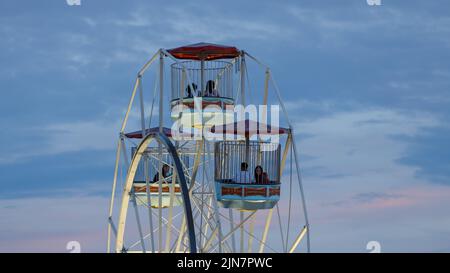 Paare sitzen in Riesenrad-Gondeln vor dem Sonnenuntergang Stockfoto