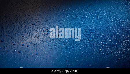 Eine Nahaufnahme von Wassertropfen auf einer blauen Oberfläche Stockfoto