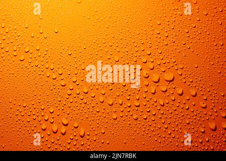 Eine Nahaufnahme von Wassertropfen auf einer orangefarbenen Oberfläche Stockfoto