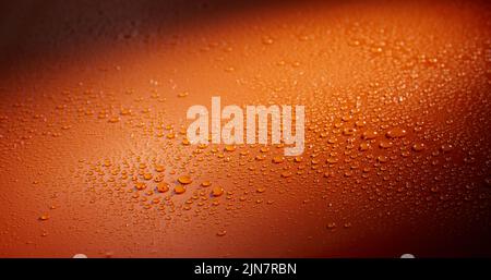 Eine Nahaufnahme von Wassertropfen auf einer orangefarbenen Oberfläche Stockfoto