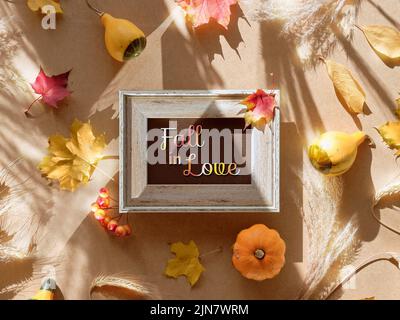 Herbstrahmen, Bildunterschrift Grußtext Fall in Love. Natürliche Herbstblätter, Weizenohren und Pampagras. Stockfoto