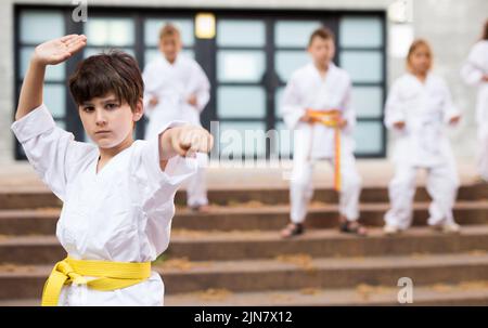 Vorteen Junge üben Karate während der Gruppenklasse auf dem Schulhof Stockfoto