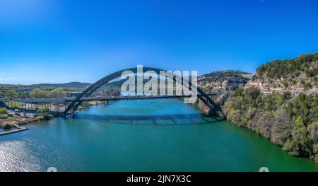 Austin, Texas - durch die Bogenbrücke und den Colorado River. Brücke verbindet das flache Land auf der linken Seite und Berggebiet auf der rechten Seite gegen die klare b Stockfoto