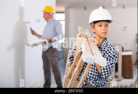 Jugendlicher, der Leiter bei der Renovierung des Hauses trägt Stockfoto