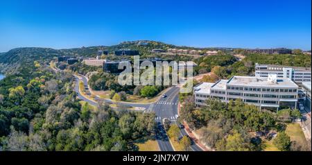 Austin, Texas - Panoramablick auf Geschäftsgebäude. Zwischen den großen Gebäuden, die von Bäumen umgeben sind, befinden sich leere Straßen und ein Blick auf die Hänge a Stockfoto