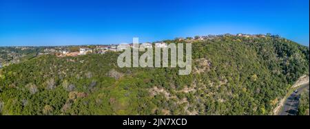 Austin. Texas - Panoramablick auf Villen und Villen auf einem Hang gegen den klaren blauen Himmel. Unten rechts befindet sich eine Autobahn Stockfoto