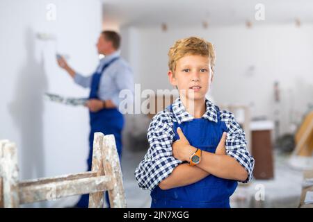 Porträt eines lächelnden Jungen, der insgesamt blau trägt Stockfoto