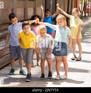 Gruppe positiver Schüler, die die Hände hochhalten und spielen Stockfoto