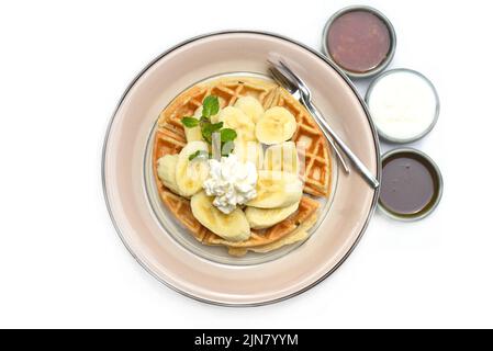 Belgische Waffeln mit Banane und Eistream auf einem Teller Stockfoto