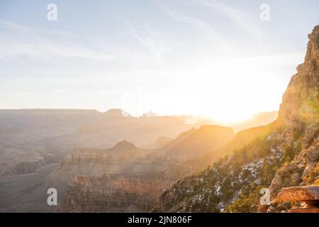 Die helle Sonne steigt über dem Rand des Grand Canyon auf und hebt den frischen Staub des Schnees hervor Stockfoto