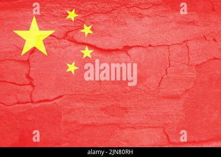 Defokussieren Sie die China-Flagge, die offiziellen Farben und den richtigen Anteil. Nationale chinesische Flagge. Steinmauer Hintergrund. Riss. Kommunismus. Nicht fokussiert. Stockfoto