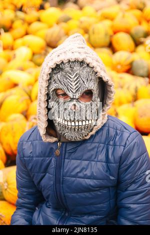 Unschärfe Halloween Menschen Porträt. Person in grimmiger Reaper Maske auf gelbem Kürbis Hintergrund stehend. Halloween-Horror. Schädelgeist. Grimmiger Schnitter. Hallo Stockfoto