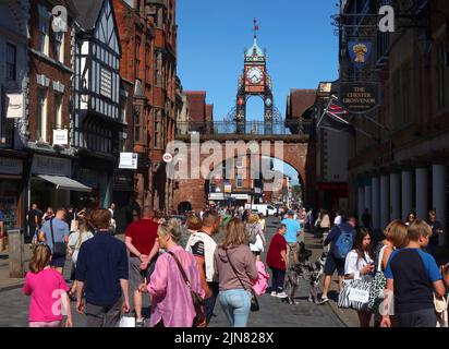 Eastgate, Einkäufer mit der berühmten Eastgate Turret Clock, über dem Eastgate der antiken Mauern von Chester, Cheshire, England, Großbritannien, CH1 1LE Stockfoto
