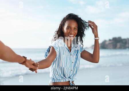Ich bin so bereit für ein bisschen Sommerspaß. POV-Aufnahme einer jungen Frau, die ihre Freunde in der Hand am Strand hält. Stockfoto