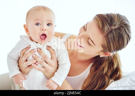 Glückliche, junge und alleinerziehende Mutter, die sich um ein entzückendes Baby kümmert, Elternschaft genießt und eine neue Mutter ist. Glückliche Frau erleben mütterliche Stockfoto