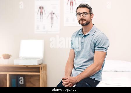 Für die Gesundheit meiner Patienten. Porträt eines hübschen reifen männlichen Physiotherapeuten, der in seinem Büro sitzt. Stockfoto