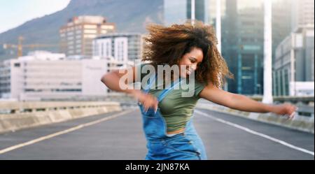 Mehr tanzen, weniger Stress. Eine attraktive junge Frau, die tagsüber im Freien einen Straßentanzablauf durchführt. Stockfoto