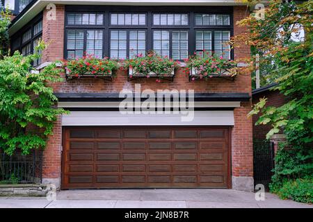Haus mit Garage für zwei Autos mit Holzmasertür im Erdgeschoss und ein Zimmer darüber Stockfoto
