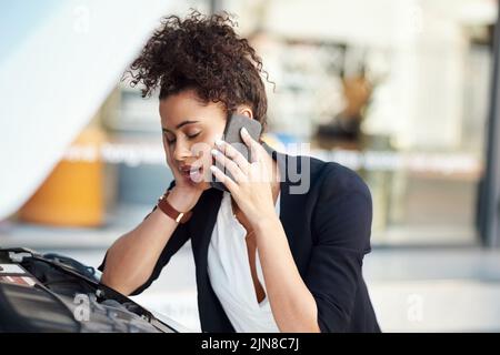 Autoprobleme frustrieren Sie in einer Minute. Eine frustrierte junge Geschäftsfrau ruft Pannenhilfe, nachdem ihr Auto zusammengebrochen ist. Stockfoto