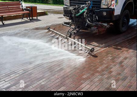 Eine spezielle Maschine wäscht Stadtwege und Straßen mit Wasser Stockfoto