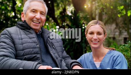 Sie kümmert sich überall um mich. Ein fröhlicher älterer Mann im Rollstuhl verbringt Zeit mit seiner Tochter draußen in einem Park. Stockfoto
