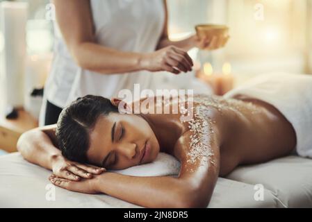 Salzpeelings verleihen der Haut einen natürlichen Glanz. Eine junge Frau erhält eine Peeling-Massage in einem Spa. Stockfoto