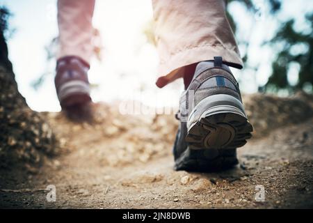 Bewegen Sie sich weiter, um die Spitze zu erreichen. Low-Angle-Aufnahme eines unkenntlichen Mannes, der tagsüber auf Felsen einen Berg hoch läuft. Stockfoto